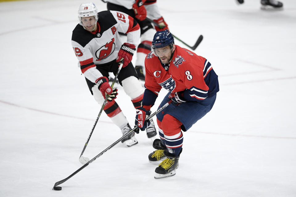Washington Capitals left wing Alex Ovechkin (8) skates with the puck in front of New Jersey Devils center Travis Zajac (19) during the second period of an NHL hockey game Tuesday, March 9, 2021, in Washington. (AP Photo/Nick Wass)