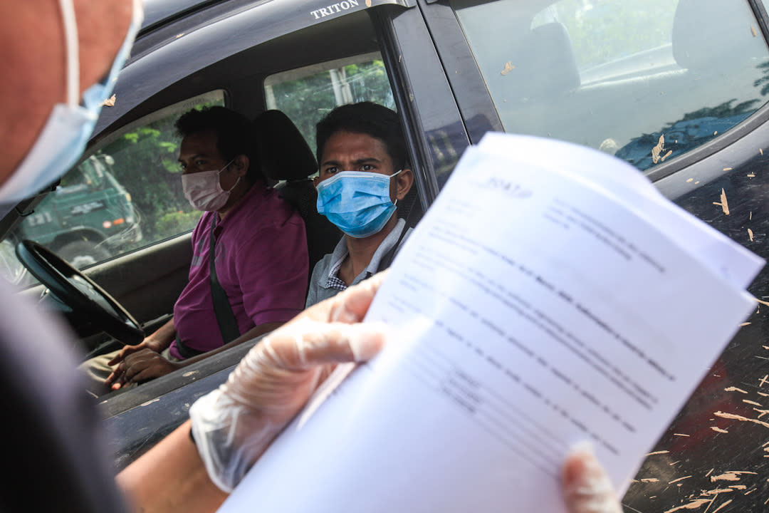 A police personnel inspects a driver’s travel documents during a roadblock at the Jawi Toll Plaza in Penang May 19, 2020. — Picture by Sayuti Zainudin