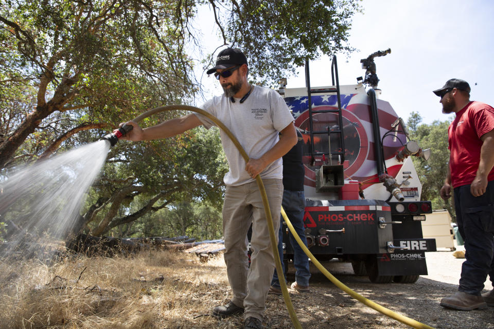 In this July 28, 2021 image provided Perimeter Solutions, Eric Clancy, left, applies a new type of long-lasting fire retardant at former President Ronald Reagan's coastal mountain ranch in the Santa Ynez mountains near Santa Barbara, Calif. U.S. officials on Tuesday, Oct. 5, 2021, approved Perimeter Solutions' new fire retardant that could significantly aid in fighting increasingly destructive wildfires. (Perimeter Solutions Photo via AP)