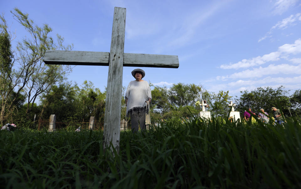 In this Wednesday May 1, 2019, photo, Alicia Jackson Flores, 68, and family walk around the the Eli Jackson Cemetery in San Juan, Texas. While the government has agreed to exempt some wildlife preserves and heritage properties from border wall construction, plenty of others remain under threat. (AP Photo/Eric Gay)