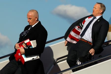 White House Director of Oval Office Operations Keith Schiller carries a red USA hat and a copy of Fortune magazine with President Trump on the cover as he and Communications Director Sean Spicer deplane from Air Force One yesterday. REUTERS/Jonathan Ernst