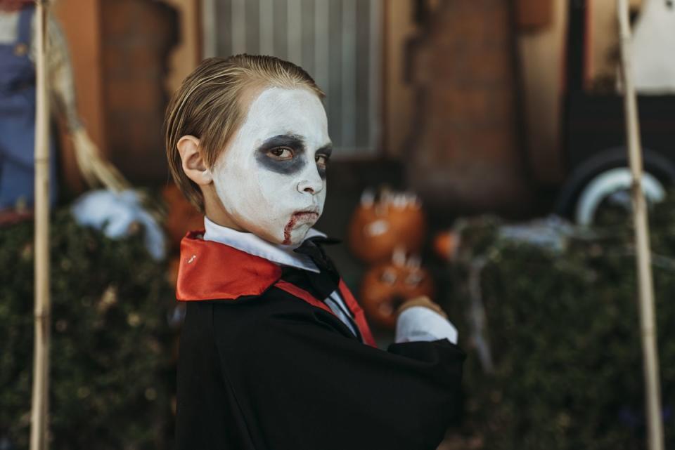 young boy dressed as dracula posing in costume at halloween