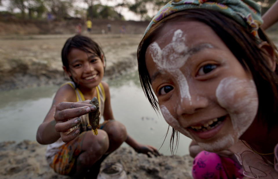 In this April 4, 2014 photo, children catch fish in an almost dried-up reservoir bed in Dala, suburbs of Yangon, Myanmar. Dwellers of Dala rely on natural fresh-water ponds for water, but during Myanmar's annual dry season in April and May, there is only so much to go around. (AP Photo/Gemunu Amarasinghe)