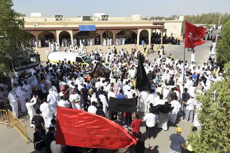 Mourners hold flags with names of Prophet Mohammad's family members as the bodies of victims of the Friday bombing are transferred to vehicles to be transported to Karbala, Iraq, at Al Jafariya cemetery in Suleibikhat, Kuwait June 27, 2015. REUTERS/Jassim Mohammed