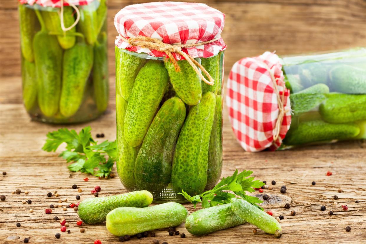 Jars of pickled marinated cucumbers on rustic table