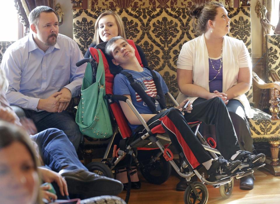 Stockton May, center, 12, waits with his sister Makayla, rear, and his mother Jennifer, right, before the H.B 105 bill signing ceremony at the Utah State Capitol, Tuesday, March 25, 2014, in Salt Lake City. Parents of Utah children with severe epilepsy are cheering a new state law that allows them to obtain a marijuana extract they say helps with seizures, but procuring it involves navigating a thorny set of state and federal laws. Utah's Republican Gov. Gary Herbert has already approved the law and held the signing ceremony Tuesday afternoon. The new law doesn't allow medical marijuana production in Utah but allows families meeting certain restrictions to obtain the extract from other states. (AP Photo/Rick Bowmer)