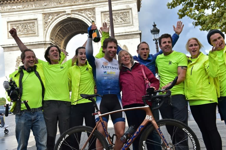 British cyclist Mark Beaumont (C) poses for pictures with his mother and members of his team after arriving at the Arc de Triomphe in Paris on September 18, 2017