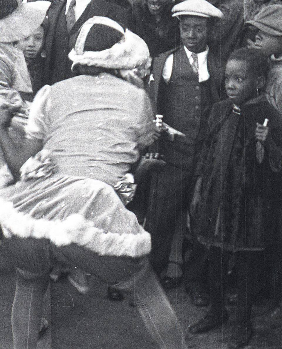 This still frame from a film strip provided by Story Sloan Gallery shows a woman dressed as "baby doll" dancing in front of a group on boys on a New Orleans street at Mardi Gras in 1931. The first known group of women to strut and dance in short “baby doll” dresses was a group of African-American prostitutes who wanted to outdo another group in 1912, but the style soon spread to respectable black neighborhoods and is seeing a modern revival. (AP Photo/Story Sloan Gallery)