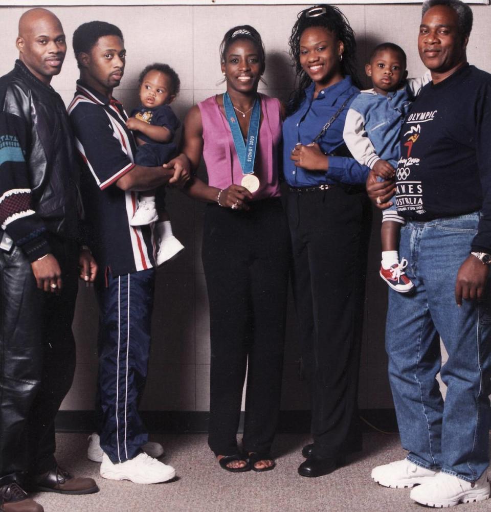 During the 2001 Olympic Games in Sydney, the Reed family takes a photo with gold medalist Ruthie Bolton (center). From left to right: Carlos Reed, Cazinova Reed (who’s holding baby Jonathon), Bolton, Tomekia Reed, John Reed (who’s holding baby Casanova).