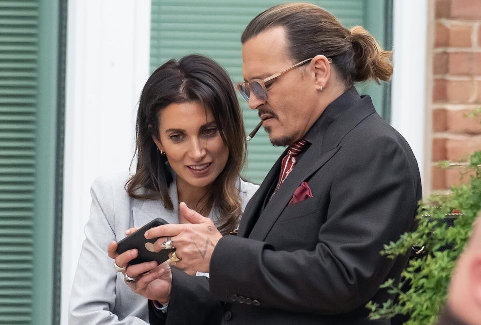 Johnny Depp look at his smartphone with his UK legal Counsel Joelle Rich during an afternoon recess outside court during the Johnny Depp and Amber Heard civil trial at Fairfax County Circuit Court on May 3, 2022 i