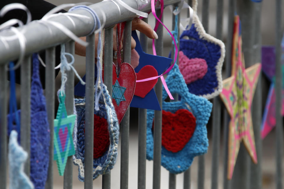 A woman ties hand-made hearts to a fence outside the Tree of Life synagogue in Pittsburgh on Sunday, Oct. 27, 2019, the first anniversary of the shooting at the synagogue, that killed 11 worshippers.(AP Photo/Gene J. Puskar)