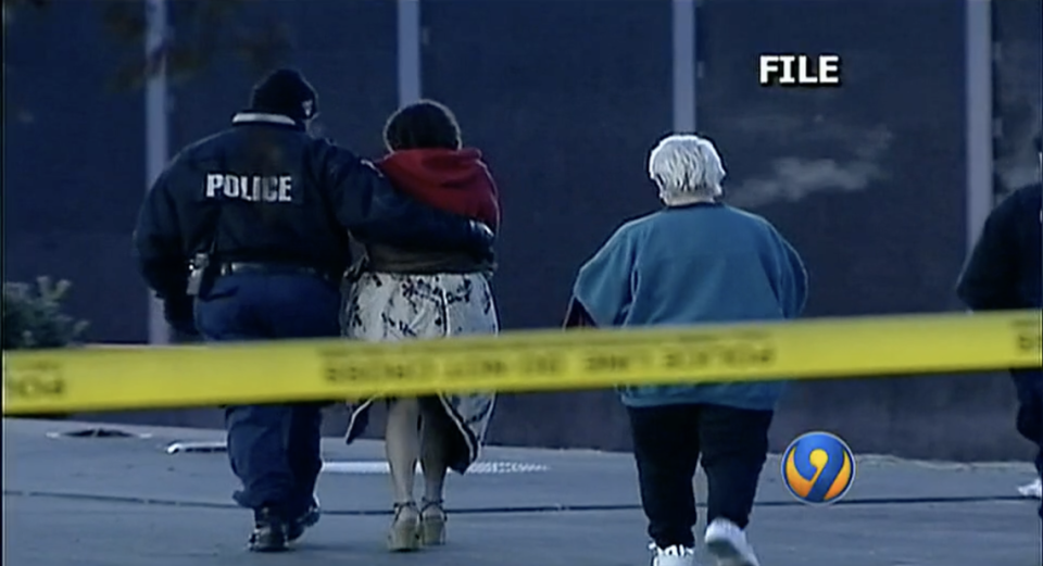 Police lead a woman away from the crime scene where Justin Ervin was murdered on Dec. 10, 2005.
