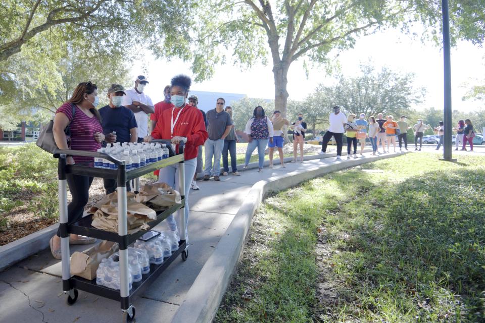 Voters wait in line as Pizza to the Polls staff hand out free food and water at a polling place in Charleston, S.C., Saturday, Oct. 24, 2020.