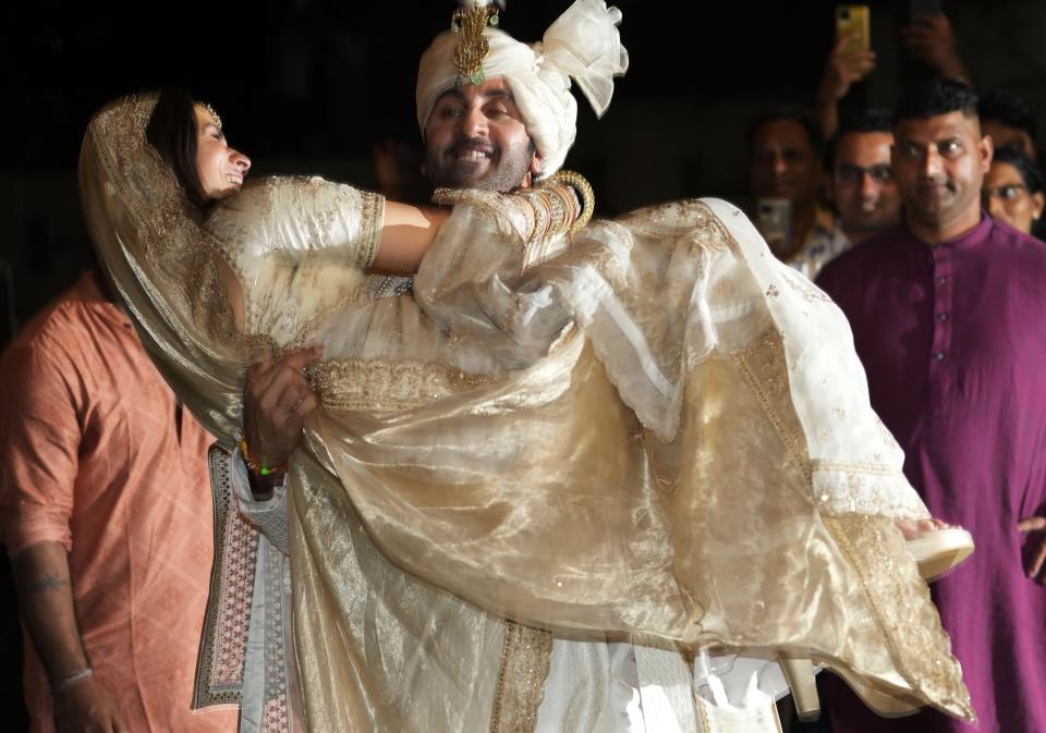 Bollywood actor Ranbir Kapoor, lifts Alia Bhatt as the couple pose for photographs after their wedding outside their residence in Mumbai, India, Thursday, April 14, 2022. (AP Photo/Rajanish Kakade)