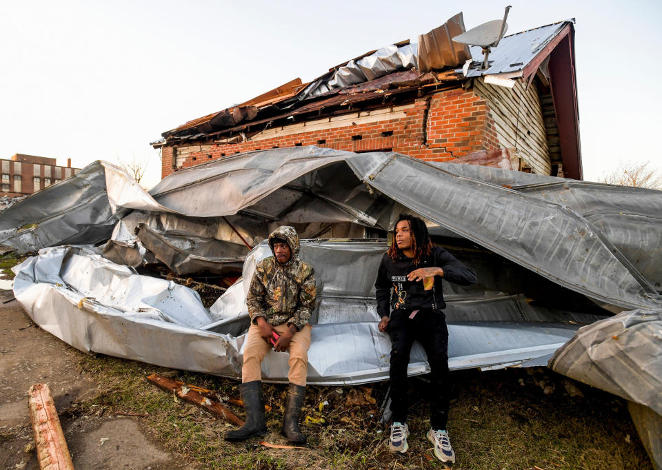 Cordel Tyus, left, and Devo McGraw sit on roofing that blew off of an industrial building and wrapped around their house in Selma, Ala. (Mickey Welsh  / USA Today Network)