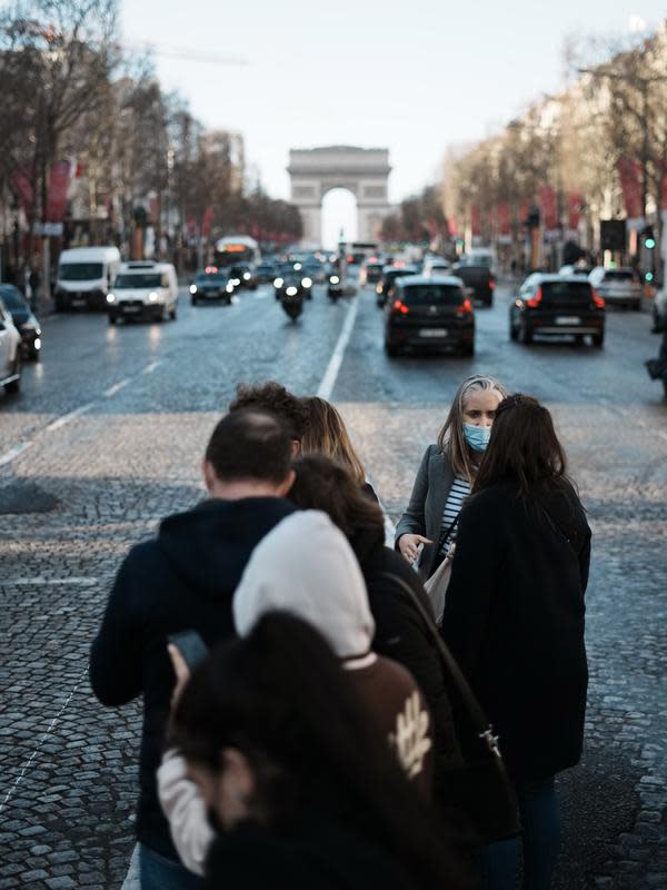 Seorang wanita mengenakan masker untuk mencegah penyebaran COVID-19, menunggu untuk menyeberangi jalan Champs Elysees, di Paris, Selasa (28/12/2021). Pemerintah Prancis telah mengumumkan langkah-langkah baru COVID-19 dalam upaya untuk mengekang penyebaran virus. (AP Photo/Thibault Camus)
