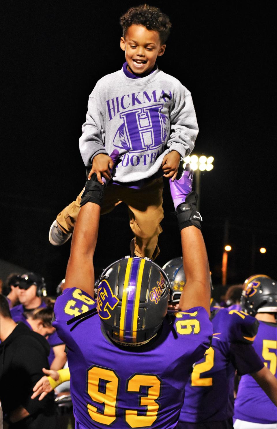 Hickman defensive tackle An'Davante Bussey (93) raises one of Kewpies' coach Cedric Alvis's sons during at timeout on the sidelines of Hickman's game against Belleville West at Hickman High School on Oct. 20, 2023, in Columbia, Mo.