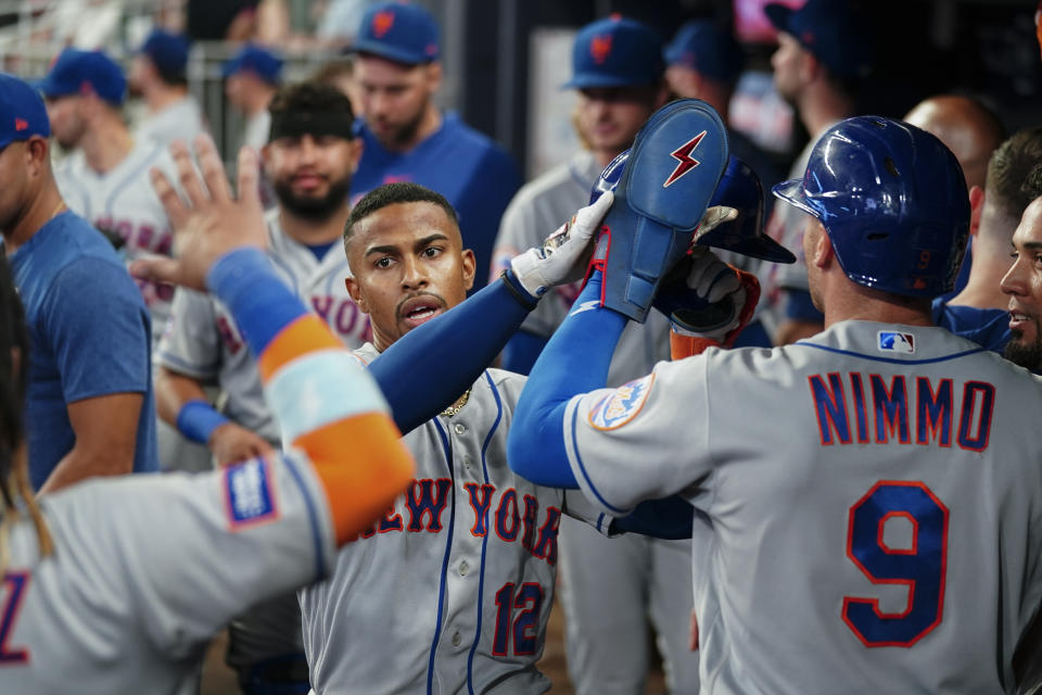 New York Mets' Francisco Lindor (12) celebrates in the dugout after hitting a three-run home run in the sixth inning of a baseball game against the Atlanta Braves, Monday, Aug. 21, 2023, in Atlanta. (AP Photo/John Bazemore)