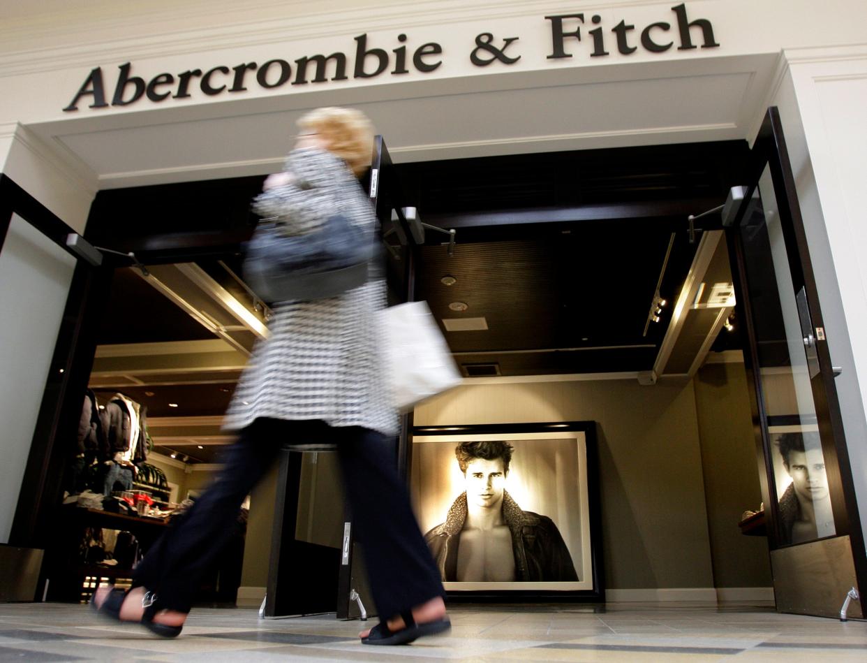 Shopper walks past entrance to Abercrombie & Fitch store with photo of male model visible