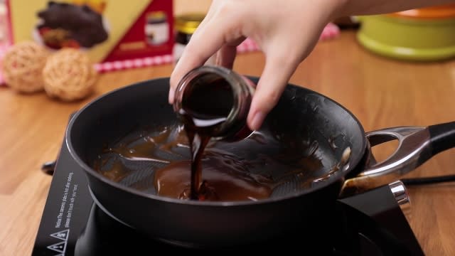 Pouring black-boned chicken essence into gravy in frying pan