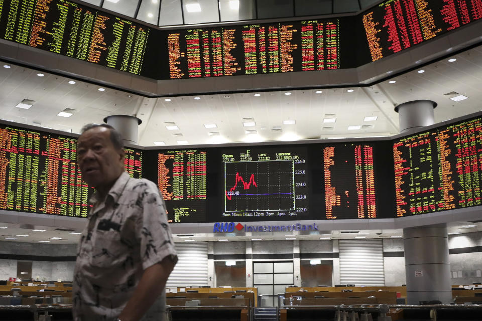 An investor walks in front of stock trading boards at a private stock market gallery in Kuala Lumpur, Malaysia, Tuesday, July 9, 2019. Asian shares mostly fell Tuesday in quiet trading as investors waited for signs on what might be ahead for U.S. interest rates. (AP Photo/Vincent Thian)