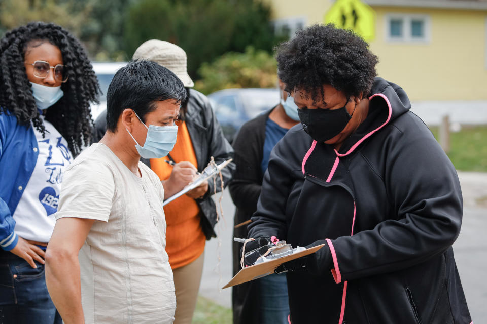 Volunteer helps man fill out paperwork to receive fresh food box and coronavirus disease (COVID-19) survival kit as part of an outreach program to the Black community to increase vaccine trial participation in Rochester, New York, U.S., October 17, 2020. Picture taken October 17, 2020.  REUTERS/Lindsay DeDario