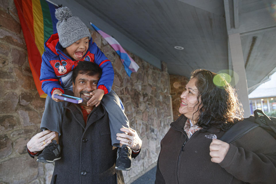 Rev. Abhi Janamanchi, left, holds Rosa Gutierrez Lopez' son John, 7, who has Down syndrome, after John arrived on the school bus to Cedar Lane Unitarian Universalist Church where the Gutierrez Lopez family is living, in Bethesda, Md., Thursday, Dec. 5, 2019. Gutierrez Lopez, who a year ago became the first unauthorized immigrant to get refuge inside a religious institution in the Washington area, has now been living in sanctuary for a year due to a deportation order. (AP Photo/Jacquelyn Martin)