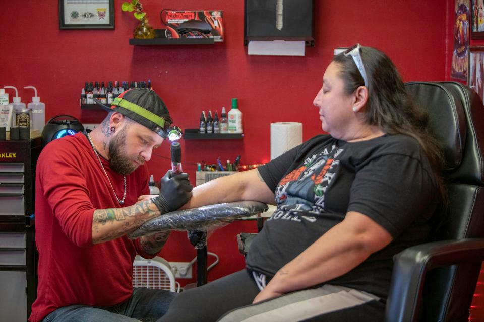 Kim Beeman receives a memorial tattoo from Michael Preston using ink mixed with the ashes of her daughter, Amelia Gutierrez, who lost her life to breast cancer.