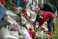 Mourners lay flowers on a wall at the Botanical Gardens in Christchurch, New Zealand, Saturday, March 16, 2019. New Zealand's stricken residents reached out to Muslims in their neighborhoods and around the country on Saturday, in a fierce determination to show kindness to a community in pain as a 28-year-old white supremacist stood silently before a judge, accused in mass shootings at two mosques that left dozens of people dead. (AP Photo/Vincent Thian)