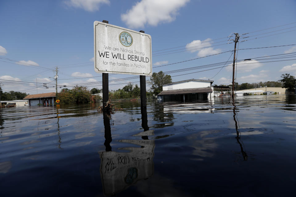 A sign commemorating the rebuilding of the town of Nichols, which was flooded two years earlier from Hurricane Matthew, stands in floodwaters in the aftermath of Hurricane Florence in Nichols, S.C., Friday, Sept. 21, 2018. Virtually the entire town is once again flooded and inaccessible except by boat. (AP Photo/Gerald Herbert)