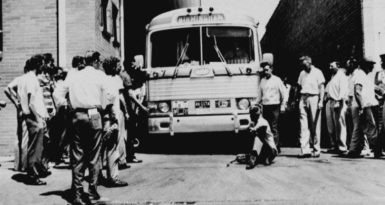 In this photo from May 15, 1961, an unidentified white man sits in front of a Greyhound bus to prevent it from leaving the station with a load of Freedom Riders testing bus station segregation in the South in Anniston, Ala. The bus was stopped by a flat tire and surrounded by a white crowd outside Anniston, and burned a short time later.