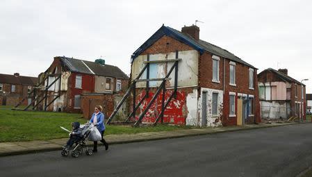 A woman pushes a pram along a semi-derelict terraced street in the Gresham area of Middlesbrough, northern Britain, January 20, 2016. REUTERS/Phil Noble