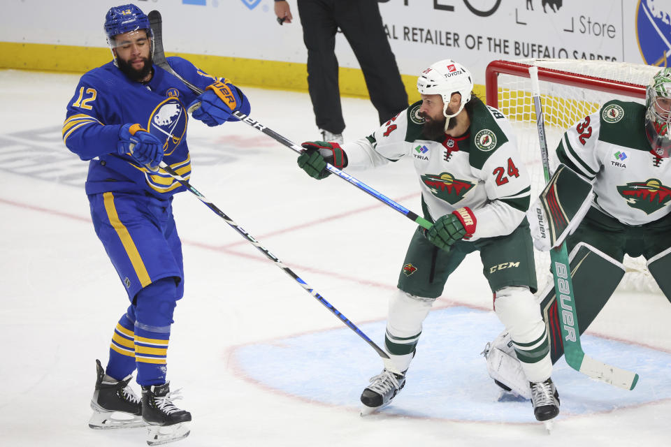 Buffalo Sabres left wing Jordan Greenway (12) and Minnesota Wild defenseman Zach Bogosian (24) work in front of the net during the third period of an NHL hockey game Friday, Nov. 10, 2023, in Buffalo N.Y. (AP Photo/Jeffrey T. Barnes)