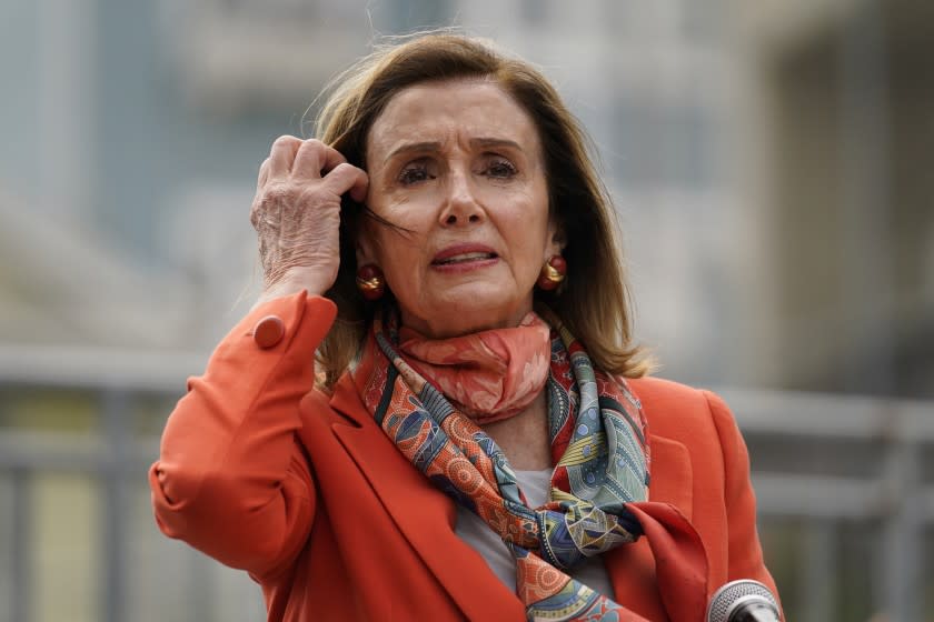 House Speaker Nancy Pelosi pulls back her hair while speaking about her visit to a hair salon.