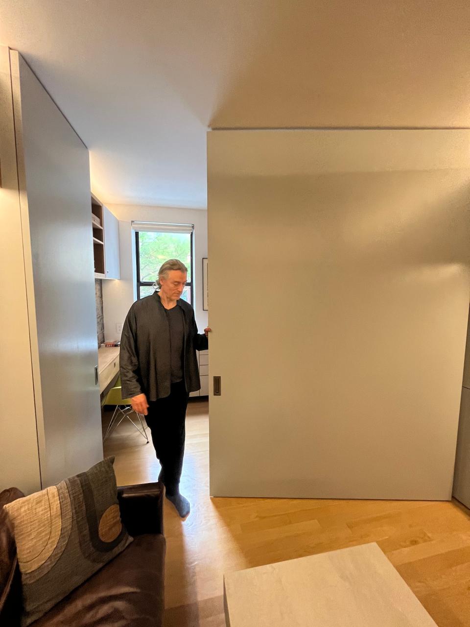 Robert Garneau locks the swinging gray wall into place to create a room divider. 