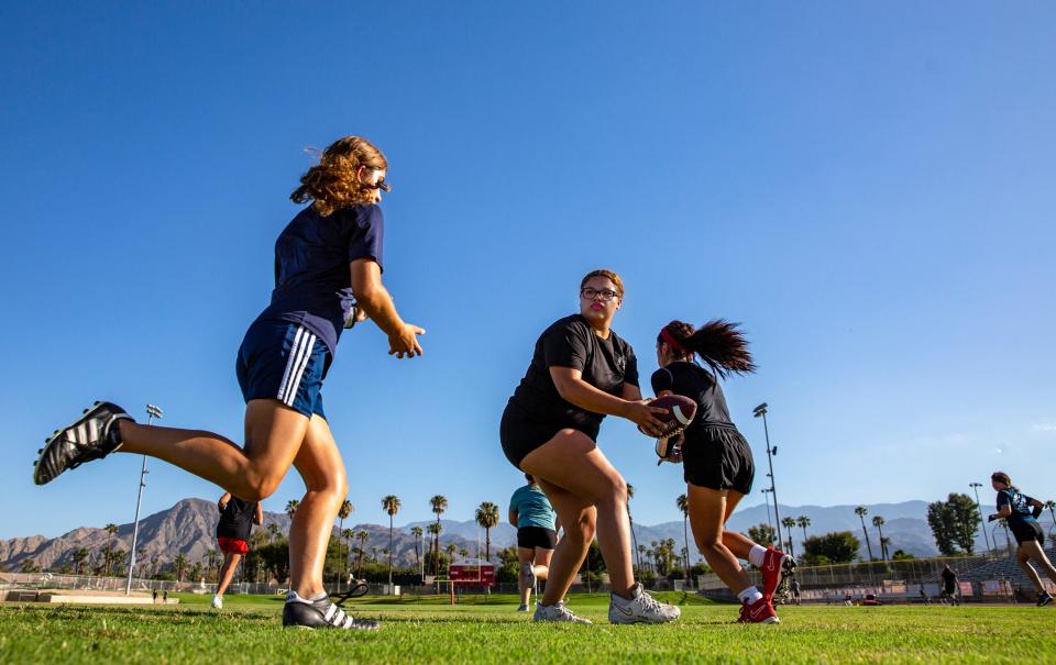 Quarterback Isabella Gonzalez fakes a handoff to one player as Madeleine Scott (left) crosses over for the handoff during practice at Palm Desert High School in Palm Desert, Calif., Thursday, Sept. 14, 2023.