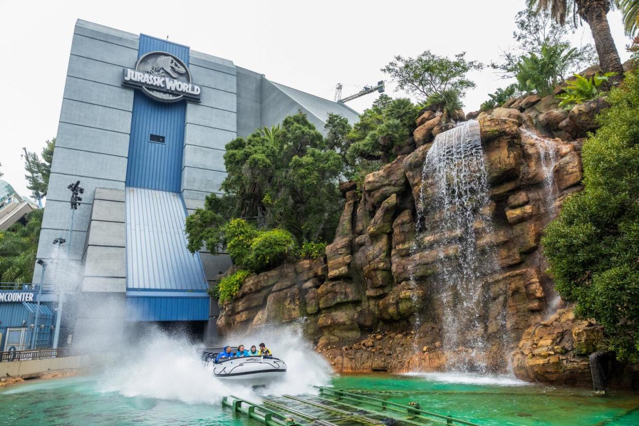 Jurassic Park water ride boat rushes through water, causing a big splash.