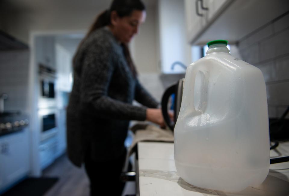 Mary Holmes cleans dishes with water from milk jugs and cooks her family dinner after she lost water in February. She filled up milk jugs with water from her work to boil and use at home. Her home also was without power for more than 65 hours.