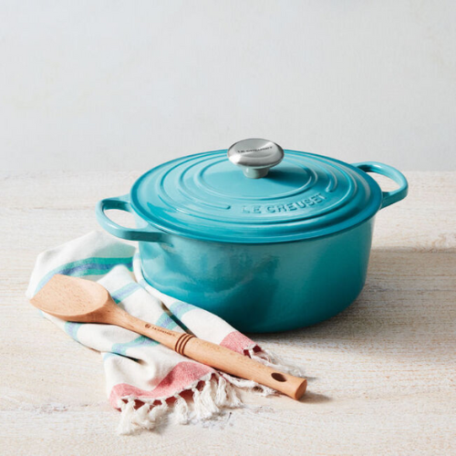 aqua blue le creuset dutch oven with wooden spatula resting on hand towel