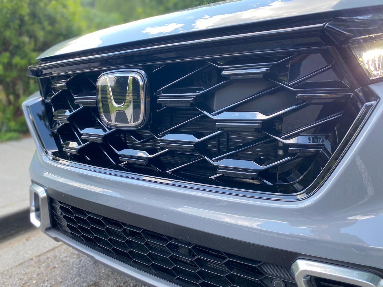 A close-up of a 2025 Honda CR-V Hybrid Sport Touring SUV's black front grille.