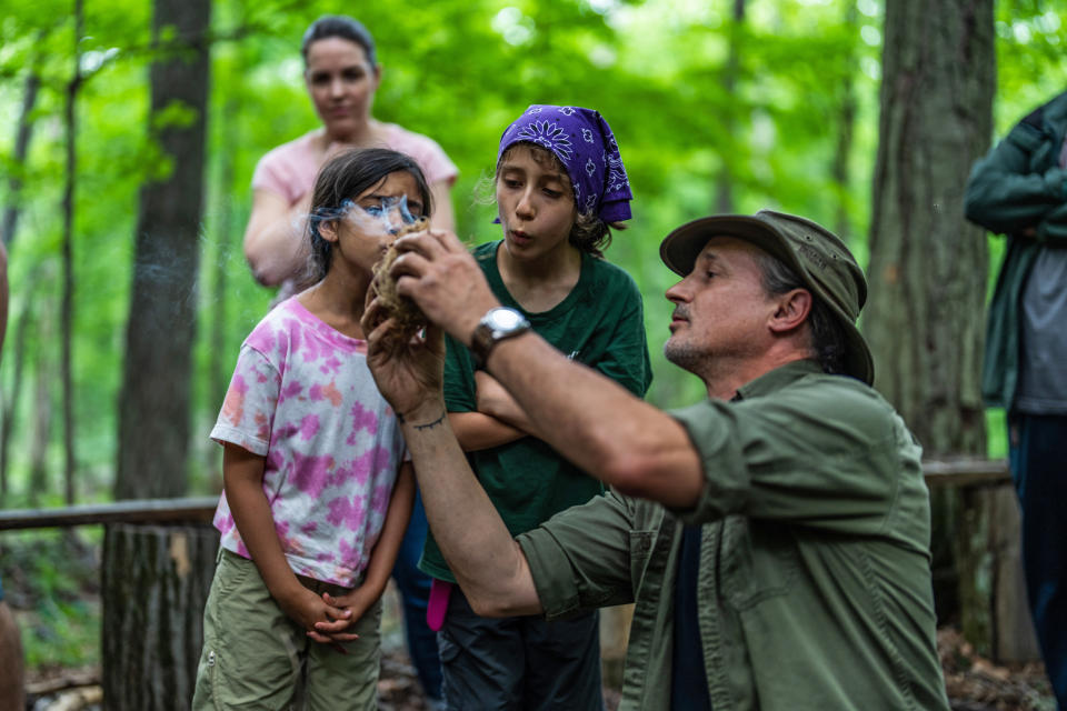 Shane Hobel puts an ember into cambium to start a fire while Sahira Pawria-Sanchez and Ara Bella Pajoohi blow on the ember. (Michael Rubenstein / for NBC News)