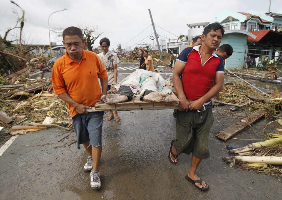 Survivors carry a person killed as super Typhoon Haiyan battered Tacloban city, central Philippines