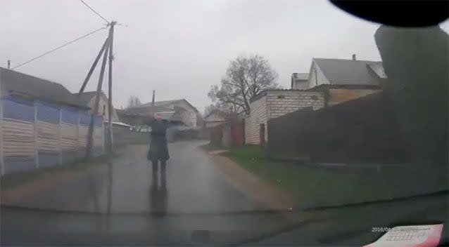 A man wearing a black raincoat appears in the middle of the road, arms stretched, forcing the driver to stop. Picture: YouTube/naf7gdrsww