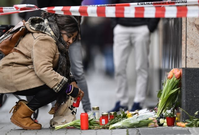 A woman sets a candle near the hookah bar scene where several people were killed in Hanau, Germany