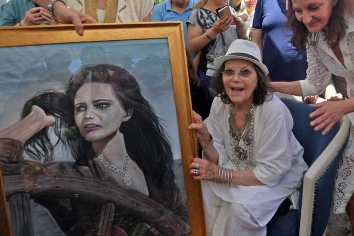 talo-Tunisian actress Claudia Cardinale (R) poses with a painting of her during the inauguration of the Claudia Cardinale street in the city of La Goulette near the Tunisian capital on May 29, 2022.