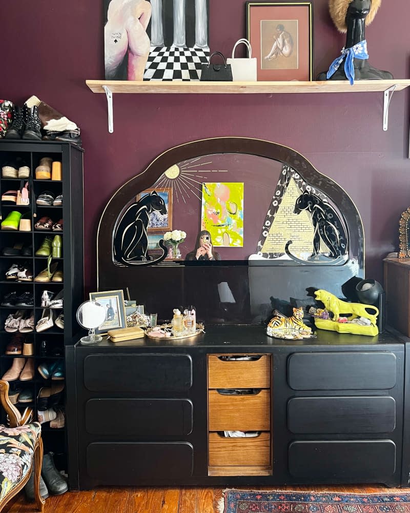 Black dresser with mirror in eggplant bedroom.