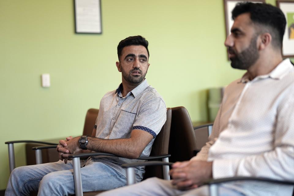 Abdul Wasi Safi, left, listens to his brother Samiullah while sitting in a dentist's waiting room, Wednesday, April 26, 2023, in Houston. Abdul's days since his release from a Texas immigration detention center have been filled with medical appointments while living in Houston with his brother. (AP Photo/David J. Phillip)