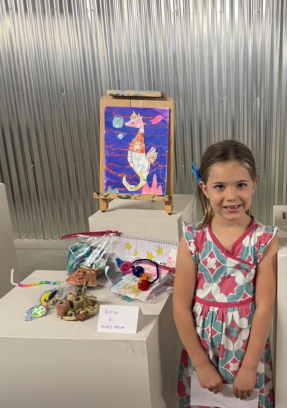 Sam Laichas' daughter Reese Overmyer, 7, presents her artwork at the end of a camp at Queen City Clay in Norwood.