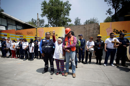 A woman, whose apartment at the Tlalpan housing project was affected by the September 2017 earthquake, raises her fist during a minute of silence to honour the victims of the quake in Mexico City, Mexico September 19, 2018. REUTERS/Daniel Becerril