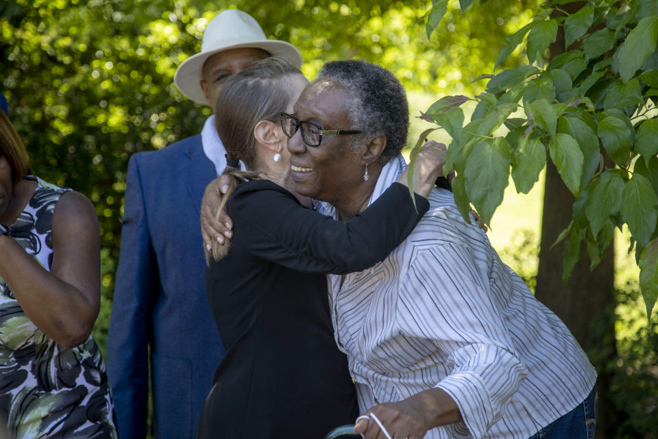 D. E. Smith, right, chair of the DeKalb Remembrance Project, which operates within the DeKalb County NAACP, receives a hug from Druid Hill resident Schaune Griffin, following a short ceremony to erect a historical marker for Porter Flournoy Turner, who was lynched in 1945, in Atlanta's Druid Hills community, Thursday, May 6, 2021. Both women participated in getting the marker installed. (Alyssa Pointer/Atlanta Journal-Constitution via AP)